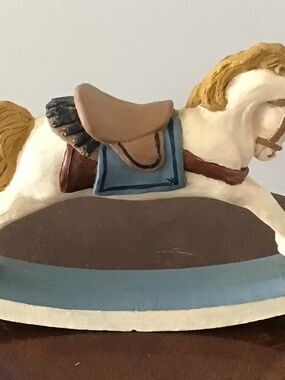 A decorative resin rocking horse figurine with a saddle and base, adorable piece